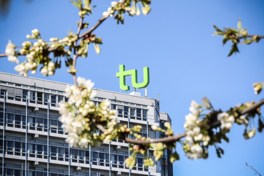 TU im Frühling_02 Das TU Gebäude umgeben von blühenden Kirschblüten.